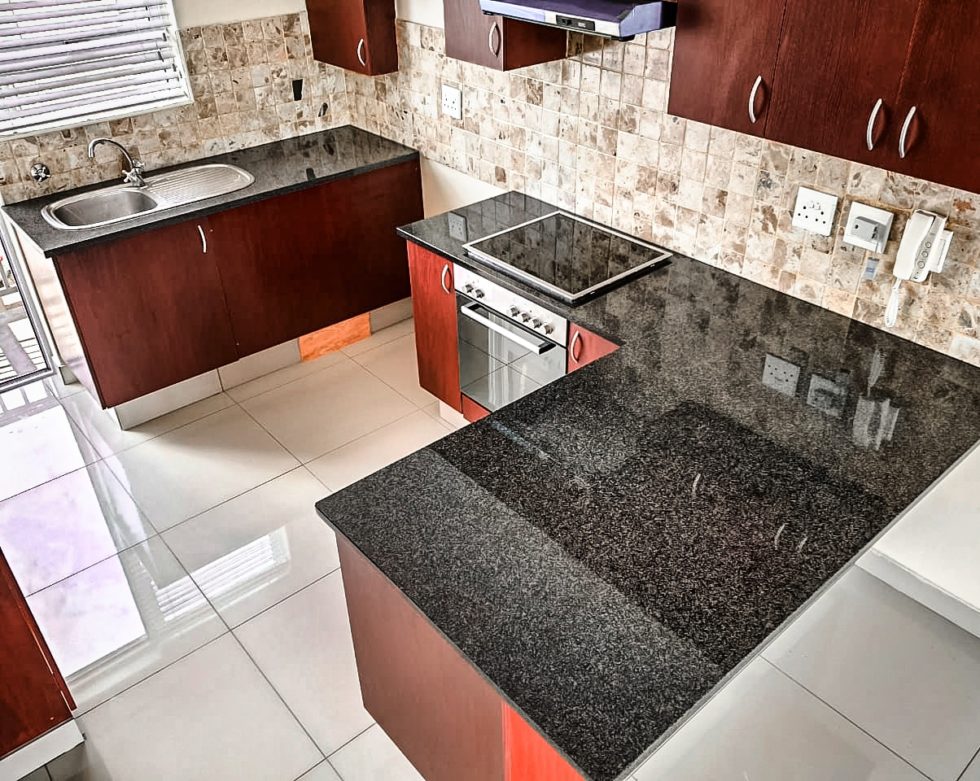 black stone countertop paired with dark brown cabinets and white tile