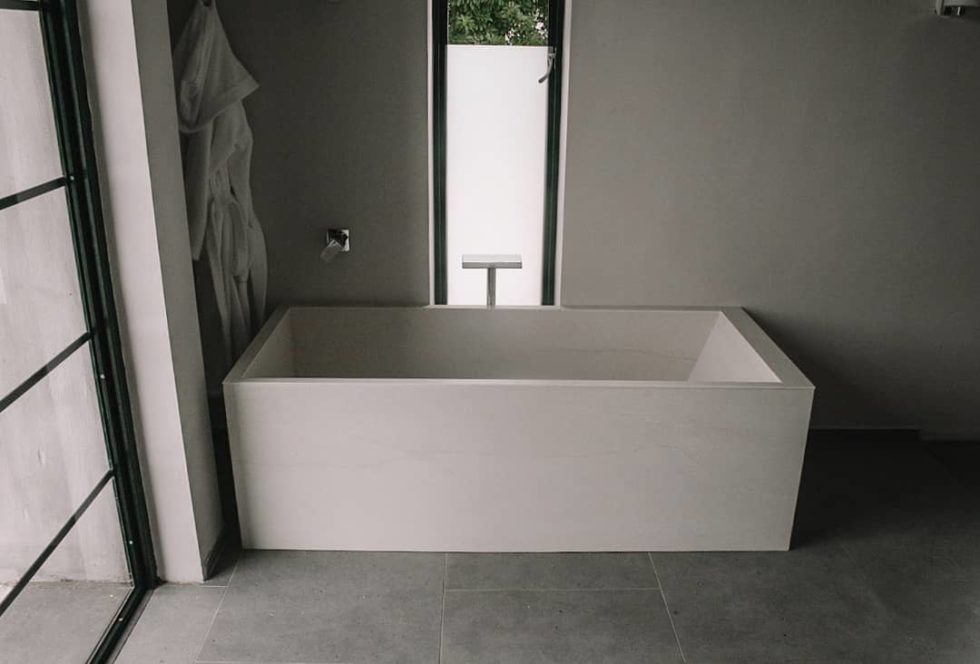 grey bathtub surrounded by grey walls and floor